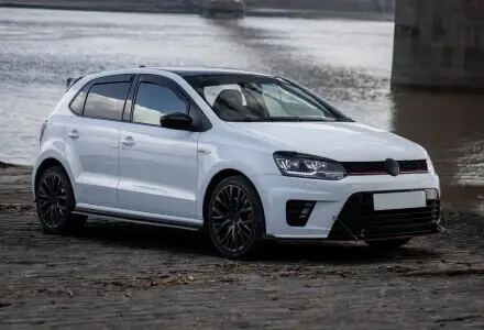 White sport hatchback parked beside an urban bridge