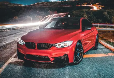 Red performance coupe photographed beside a winding road